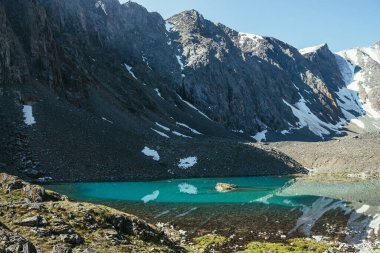 Karlı dağ, buzul gölünün berrak sularına yansıyor. Berrak gökyüzünün altındaki dağ gölünün su yüzeyinde buzul yansıması olan güzel güneşli bir manzara. Dağdaki gölde yansıyan karlar..