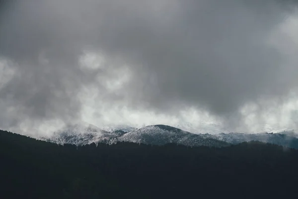 阴云密布的天气里 黑暗的大气景观 雪山密布 云雾密布 在雪山之上的灰蒙蒙的雨云和山形轮廓之上的极简主义阴暗的风景 微小的云彩 — 图库照片