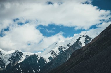 Harika dağ manzarası ve karlı dağ tepesi. Kar beyazı yüksek dağlı buzullu atmosferik manzara. Karlı büyük dağlar. Beyaz karlı dev siyah kayaların manzarası.