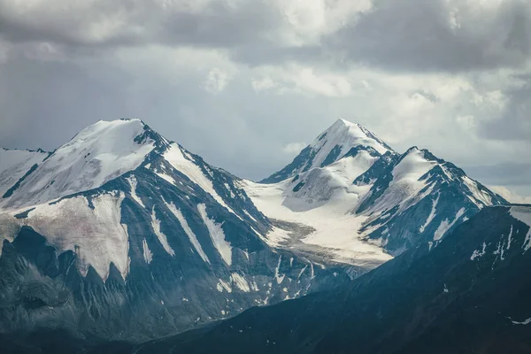 曇り空の下で大きな雪の山の尾根と劇的な山の風景 曇りの日に高い山脈と暗い大気高地の風景 灰色の雲の下で素晴らしい大きな山 — ストック写真