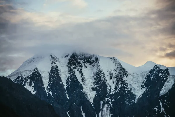 日没や色を照らす日の出曇りの空を背景に 低雲の中で雪の山の頂上と最小限の高山風景 明け方の空に雪の白い山の尾根と大気の風景 — ストック写真