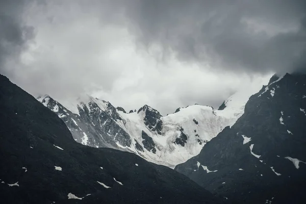 黑色岩石上的冰川在铅灰色多云天空中的黑暗的大气山地景观 多雪的高山 多云的低洼地区 多雨的天气 多山多山 — 图库照片