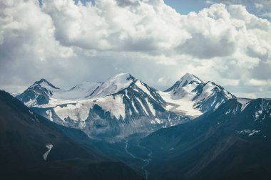 Atmosferik alp manzaralı buzullu karlı dağlara. Tepelerinde kar olan dağlarla muhteşem dağlık arazi manzarası. Buzulları ve eriyen su akıntılarıyla inanılmaz bir dağ manzarası..