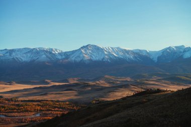 Kırmızı vadiyi gören turistlerle dolu muhteşem sonbahar manzarası ve kırmızı gün batımında karla kaplı dağ sıraları. Kar dağları ve sonbahar vadisinin güneşli manzarası.