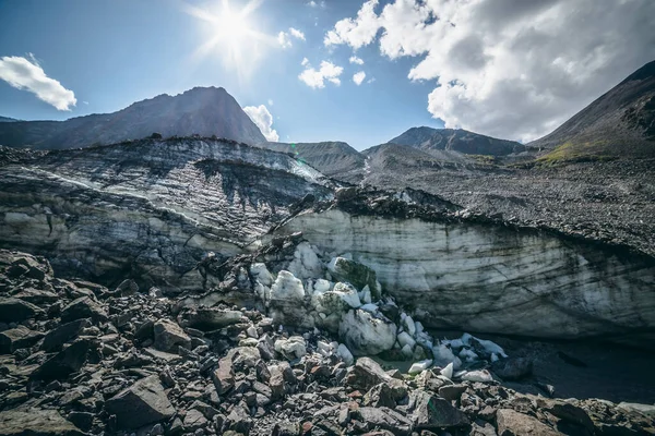 Yüksek dağ zirvesinin arka planındaki morinalar arasında çizikler olan büyük çatlamış buzullu manzaralı dağlık arazi. Muazzam dağ manzarası Büyük buzullu ve büyük dağ tepeli.