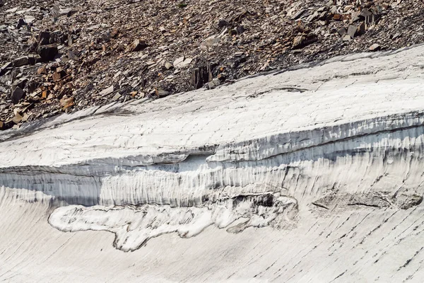 Minimal nature backdrop with glacier on stony mountainside close up. Minimalist natural background with beautiful snow cornice on steep slope. Closeup of glacier surface. Minimalism with snow cornice.