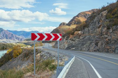 Renkli sonbahar manzarası, gün ışığında kayalar boyunca uzanan dağ yolu. Sonbahar renklerinde dağ yolu olan parlak alp manzarası. Sonbahar zamanı dağlarda otoyol. Yol boyunca güzel kayalık duvar boyunca.