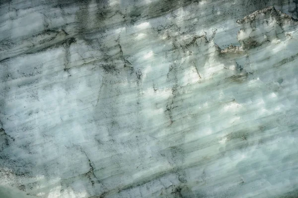 Minimalist nature background of glacier surface with cracks and scratches close up. Minimal natural backdrop of icy wall in sunlight. Shiny glacial surface. Beautiful nature texture of glacial wall.