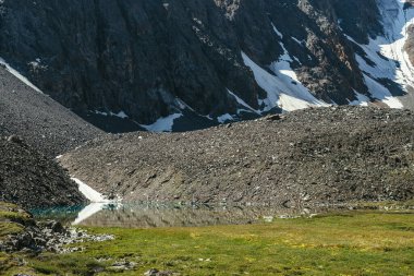 Stony Dağı yakınlarında karlı dağ gölü olan renkli yeşil bir manzara. Dağ gölünün berrak su yüzeyine sahip güzel manzaralı bir yer. Güneş ışığında gök mavisi bir buzul gölü. Turkuaz buzul gölü.
