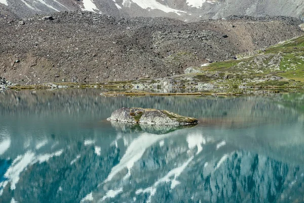 청록색 호수에 바위가 호수의 반사된 눈덮인 눈처럼 호수의 표면에 반사되는 — 스톡 사진
