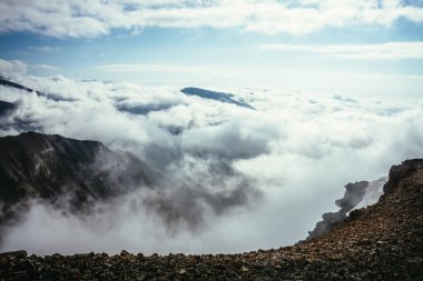 Bulutların üstündeki dağın tepesindeki atmosferik manzara kalın alçak bulutlarda tepe noktasına kadar. Uçurumun kenarından bulutların üzerinden minimalist görüş. Yoğun bulutların üzerindeki dağ sırasıyla güzel bir manzara..