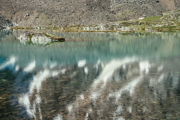 ターコイズブルーの山の湖の岩 雪の山氷河湖の紺碧の澄んだ水に反映されます 雪と美しい晴れた背景 山の湖の緑の水面に白い氷河の反射 — ストック写真