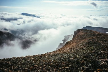 Bulutların üstündeki dağın tepesindeki atmosferik manzara kalın alçak bulutlarda tepe noktasına kadar. Uçurumun kenarından bulutların üzerinden minimalist görüş. Yoğun bulutların üzerindeki dağ sırasıyla güzel bir manzara..