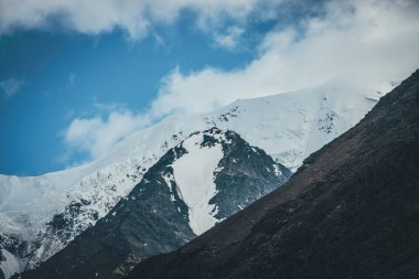 Harika dağ manzarası ve karlı dağ tepesi. Kar beyazı yüksek dağlı buzullu atmosferik manzara. Karlı büyük dağlar. Beyaz karlı dev siyah kayaların manzarası.