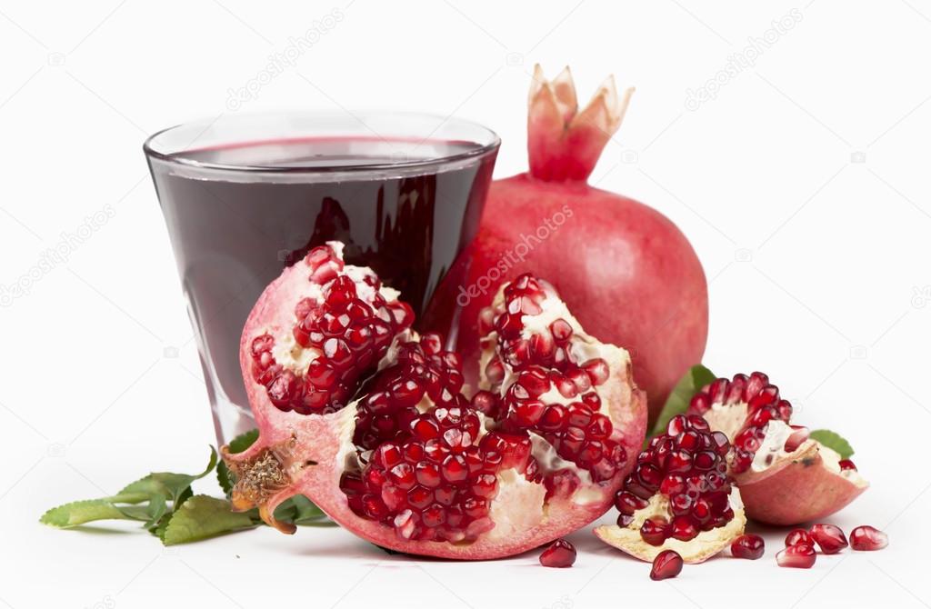 Garnet juice in a glass and pomegranate on the white