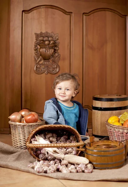 Boy among baskets with vegetables — Stock Photo, Image