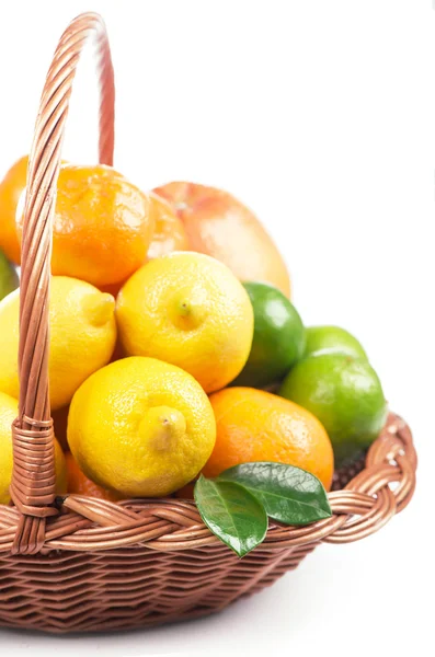 Färska citrusfrukter med blad i en flätad korg — Stockfoto