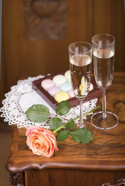 Rose, two champagne glasses and  macaroons — Stock Photo, Image