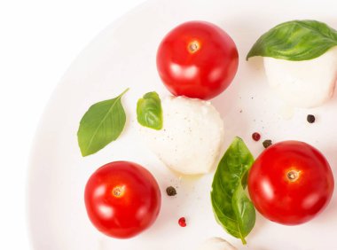 Kiraz domates ve fesleğen beyaz bir plaka üzerinde yuvarlak camembert peyniri.