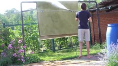 Özel ev temizliği, halı yıkama, halı yıkama. Genç bir adam kirli bir halıyı çamaşır makinesiyle yıkar.