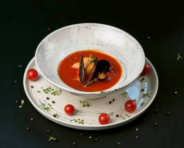 Norman balığı çorbası. Siyah arka planda bir tabakta deniz mahsulü.