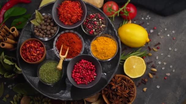 Collection of spices. Dried various herbs and spices for cooking in bowls on a black table. View from above — Stock Video
