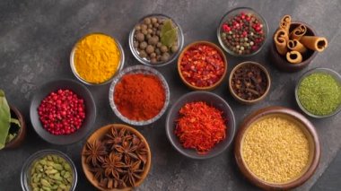 Baharat koleksiyonu. Siyah bir masada yemek pişirmek için çeşitli otlar ve baharatlar. Yukarıdan görüntüle