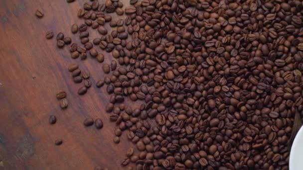 Pachnące ziarna kawy i biały kubek z kawą na drewnianym stole — Wideo stockowe