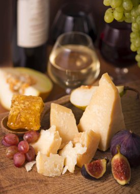 Üzüm, kavun, incir, kraker, bal, fındık ve beyaz şarapla servis edilen peynir tabağı.