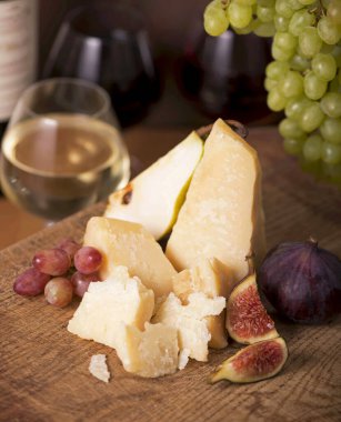 Üzüm, kavun, incir, kraker, bal, fındık ve beyaz şarapla servis edilen peynir tabağı.