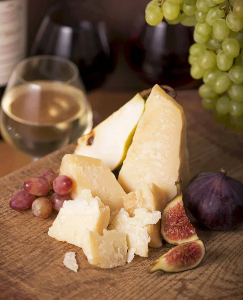 Üzüm, kavun, incir, kraker, bal, fındık ve beyaz şarapla servis edilen peynir tabağı.