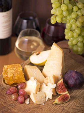 Üzüm, kavun, incir, kraker, bal, fındık ve beyaz şarapla servis edilen peynir tabağı.