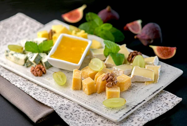 Çeşit çeşit peynirli peynir tabağı - gorgonzola, mozzarella, camembert, toma, emmental ve taze kaprino siyah arka planda