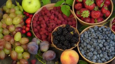 Eski bir ahşap masanın üzerinde çilek, yaban mersini, ahududu ve tatlı kiraz çilek çekim renkli çeşitli karışımı. Yaprakları ile çeşitli sulu çilek.