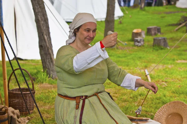 Kvinna i medeltida miljö och kostym spinna garn. Stockfoto