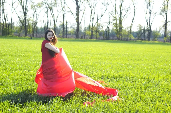Jonge dame in rode jurk op veld — Stockfoto