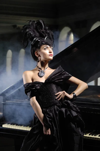 Elegant lady with luxurious hairstyle near piano — Stock Photo, Image