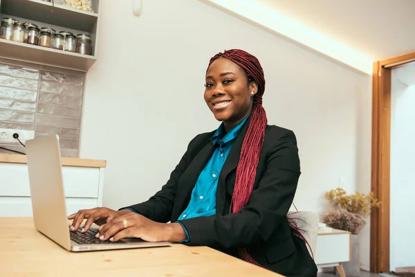 black business woman working on laptop wearing a blue shirt