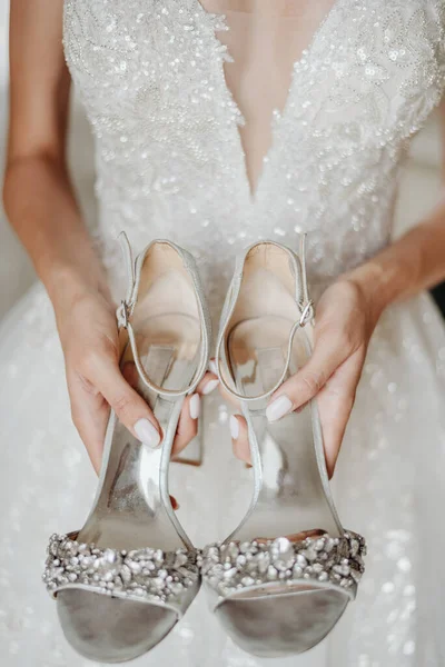 Bruid Een Witte Trouwjurk Houdt Zilveren Schoenen Met Edelstenen Haar — Stockfoto