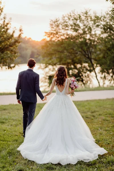 Das Brautpaar Hochzeitstag Bei Sonnenuntergang Beim Spaziergang Park Händchen Haltend — Stockfoto