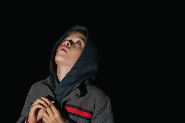 フード付きの暖かい服を着た小さな男の子が暗闇の中で空を見る — ストック写真