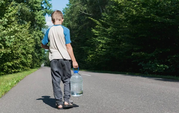 Mały Chłopiec Niesie Dużą Butelkę Czystej Wody Wzdłuż Drogi — Zdjęcie stockowe
