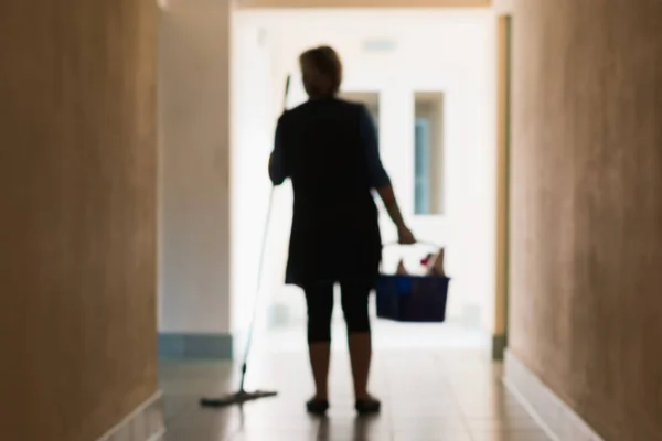 A blurry image of a woman cleaning the premises during the cleaning of the corridor and office