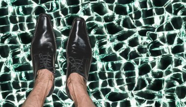 Kırık camlarda model ayakkabılar giyen yetişkin bir adamın bacakları.