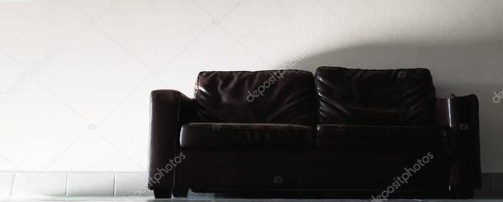 Tinted image of a dark-colored leather sofa in the hallway of an office building