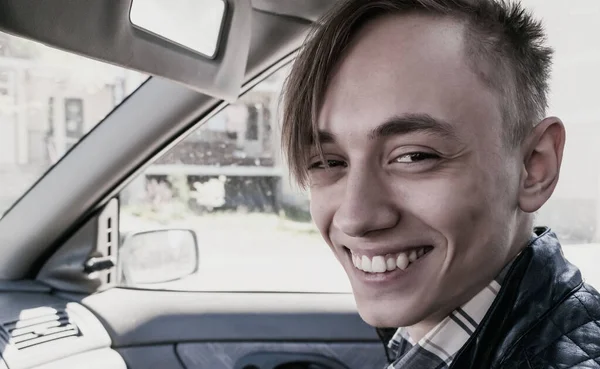 車の中に座っている若い男がカメラで微笑んだ — ストック写真