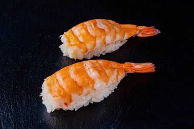 Suşi dürümleri siyah taş üzerine servis edilir. Siyah arka planda.
