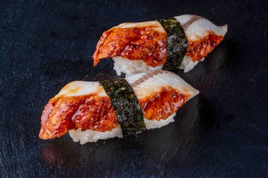 Suşi dürümleri siyah taş üzerine servis edilir. Siyah arka planda.