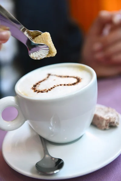 Cubo de açúcar é colocado em uma xícara de cappuccino — Fotografia de Stock