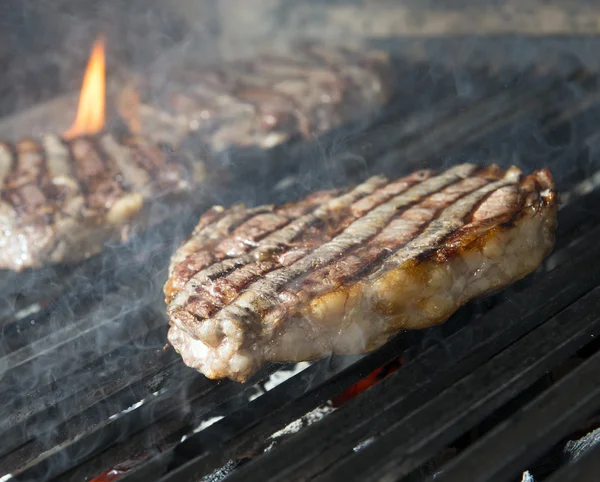 Bife de carne cozinhando em uma grelha de chama aberta — Fotografia de Stock